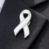 A white ribbon pin with silver edging, placed on a black fabric background. The pin's smooth, glossy surface contrasts with the dark fabric.