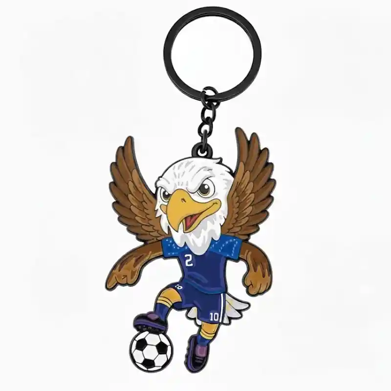 A cartoon eagle mascot wearing a blue soccer jersey with the number 2, kicking a soccer ball while flying with its wings spread, attached to a keychain.