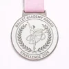 A silver ballet academy award medal with a dancer in mid-pose, surrounded by a laurel wreath. The inscription reads "BALLET ACADEMY AWARD" at the top and "EXCELLENCE 2026" at the bottom.