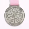 A silver ballet competition medal featuring a ballerina in a pose with flowing ribbons, surrounded by intricate swirling patterns. The inscription reads "BALLET COMPETITION" at the top and "FINISHER 2026" at the bottom.