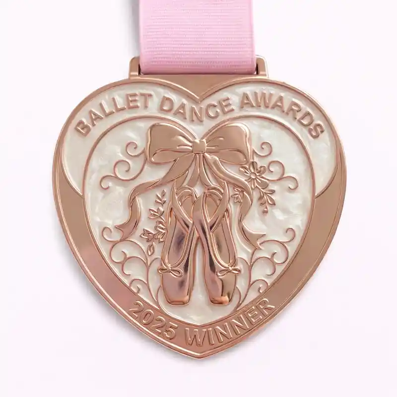 A rose gold ballet dance award medal shaped like a heart, featuring ballet shoes tied with a ribbon and floral accents. The inscription reads "BALLET DANCE AWARDS" at the top and "2025 WINNER" at the bottom.