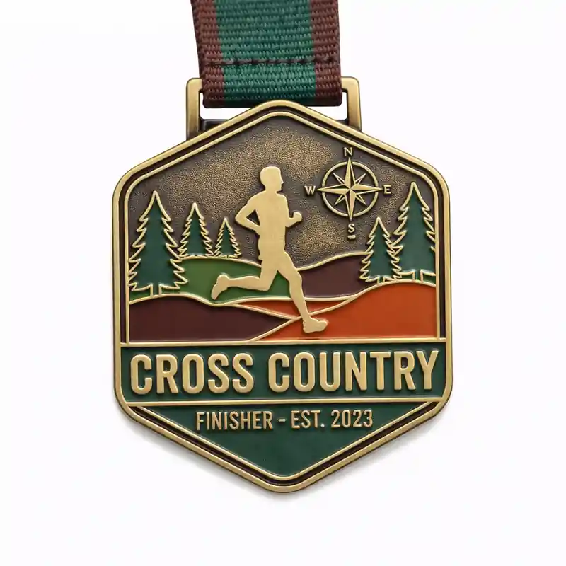 A bronze Cross Country finisher medal featuring a runner in a forest landscape, with a compass rose in the top corner. The medal is inscribed with "CROSS COUNTRY FINISHER" at the bottom, and "EST. 2023" in a banner, symbolizing achievement in cross-country running.