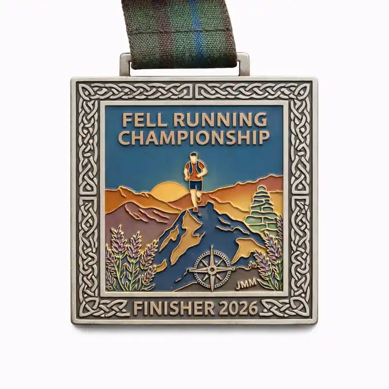 A silver finisher medal for the Fell Running Championship 2026, featuring a runner on a mountain trail with a sunset in the background. The medal includes a compass and is surrounded by Celtic knotwork along the edges. The top reads "FELL RUNNING CHAMPIONSHIP" and the bottom states "FINISHER 2026."