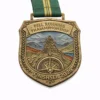 A bronze finisher medal for the Fell Running Championship 2026, featuring a cairn (stone stack) atop a mountain with a compass below. The medal is inscribed with "FELL RUNNING CHAMPIONSHIP" and "FINISHER 2026," with a scenic mountain backdrop and a green and yellow ribbon.