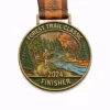 A bronze Forest Trail Classic finisher medal depicting a runner along a scenic forest trail, with lush trees and a winding stream. The medal is inscribed with "FOREST TRAIL CLASSIC" at the top, "2024" at the bottom, and "FINISHER" in the center, symbolizing the completion of the race.