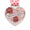 A silver heart-shaped medal featuring red and pink roses with the inscription "FOREVER & ALWAYS" and "MY ONE AND ONLY," along with a pink ribbon adorned with heart patterns.