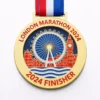 A gold medal featuring the London Eye and Big Ben with the inscription "LONDON MARATHON 2024" and "2024 FINISHER" at the bottom, along with a red, white, and blue ribbon attached.