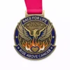A bronze medal featuring a phoenix rising above flames, symbolizing strength and resilience in the fight against cancer. The medal includes the words "RACE FOR LIFE 2026" at the top and "RISE ABOVE CANCER" at the bottom, with a heart-shaped symbol in the center.