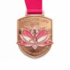 A medal featuring a pink lotus flower with a running figure at its center. The top of the medal reads "RACE FOR LIFE 2026" and the bottom reads "TOGETHER WE BEAT CANCER."