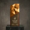 Trophée en aluminium aérospatial et base en bois de rose, avec un sommet géométrique et une plaque métallique gravée sur une plateforme en marbre.