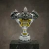 Trophée de championnat sur le thème de la fantasy, représentant un guerrier en armure finement sculpté orné d'une plaque emblématique dorée, symbolisant une récompense dans le domaine du jeu vidéo de compétition, posé sur un socle en marbre