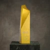 Grand trophée d'entreprise en or au design géométrique élégant, gravé du logo HSBC et du nom du récipiendaire, présenté sur un socle en marbre.