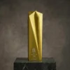 Trophée en étoile à cinq branches en or givré avec un grand motif géométrique facetté, gravé avec les détails de la réalisation et présenté sur une base en marbre foncé.