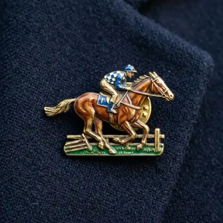 Enamel lapel pin featuring a jockey riding a racehorse jumping over a hurdle, worn on a dark jacket.