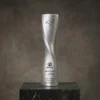 Trophée à colonne torsadée en argent avec un design en spirale lisse et un logo et un texte gravés, présenté sur une base en marbre foncé.