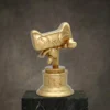 Trophée en or de la figurine de la mascotte de Tmall avec un mignon dessin animé, reposant sur un socle rond gravé d'un texte en chinois, présenté sur une plate-forme en marbre.