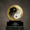 Trophée de championnat circulaire en or sur le thème du yin et du yang avec un motif en noir et blanc, monté sur un socle noir gravé des détails du championnat Fight Club.
