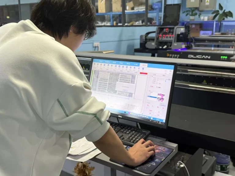 レーザー彫刻機に接続されたコンピューターで設計ソフトを操作し、メダル製造のための詳細なレイアウトを準備している技術者。