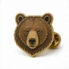 Épingle à tête d'ours brun Épingle en émail mou avec des contours métalliques en relief, des sections de couleur émaillée plate, des détails de badge connectés et une pochette de papillon sur fond blanc.