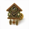 Klassische Kuckucksuhr-Anstecknadel aus weicher Emaille mit erhabenen Metallkonturen, flachen Emaille-Farbabschnitten, verbundenen Abzeichendetails und einem Schmetterlingsgriff auf weißem Hintergrund.
