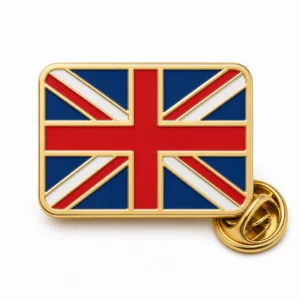 Spilla con bandiera classica Union Jack con contorni in rilievo in metallo dorato, bande di bandiera smaltate rosse, bianche e blu, forma rettangolare arrotondata e frizione a farfalla su sfondo bianco.
