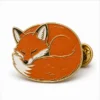 Мягкая эмалевая булавка Curled Red Fox Pin с рельефными металлическими контурами, плоскими цветными участками эмали, соединенными деталями значка и муфтой в виде бабочки на белом фоне.