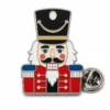 Pin de cascanueces de tambor mayor con contornos de metal plateado pulido, sombrero negro alto, chaqueta roja, barba blanca, paneles azules y un embrague de mariposa sobre blanco.