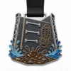 Медаль с препятствиями Tough Mudder Medal из мягкой эмали с контурами из полированного серебристого металла, черной лентой, перекладинами скалодрома, подъемом по канату, принтом грязных ботинок, панелями с брызгами воды и белым фоном.