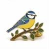 Perched Blue Tit Pin ソフト・エナメルのピン。メタルのアウトラインが浮き上がり、エナメルのカラー部分がフラットになり、バッジのディテールがつながり、白地に蝶のクラッチがあしらわれている。.