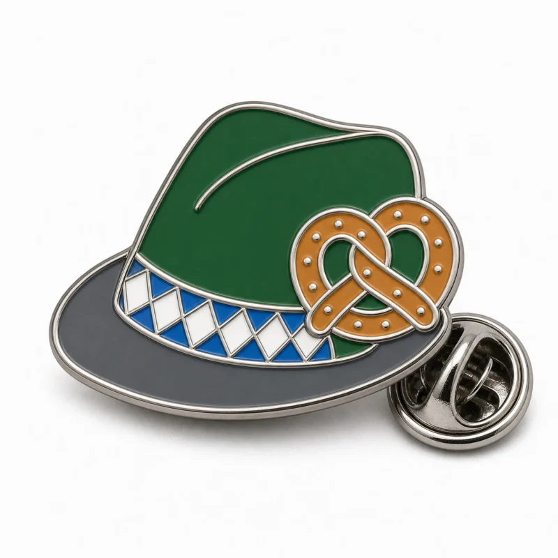 Spilla per cappello bavarese a tesa pretzel con contorni in metallo argentato lucido, cappello verde, dettaglio pretzel abbronzato, fascia bianca blu e frizione a farfalla su sfondo bianco.