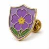 Purple Shield Primrose Pin soft enamel pin with raised metal outlines, flat enamel color sections, connected badge details, and a butterfly clutch on a white background.
