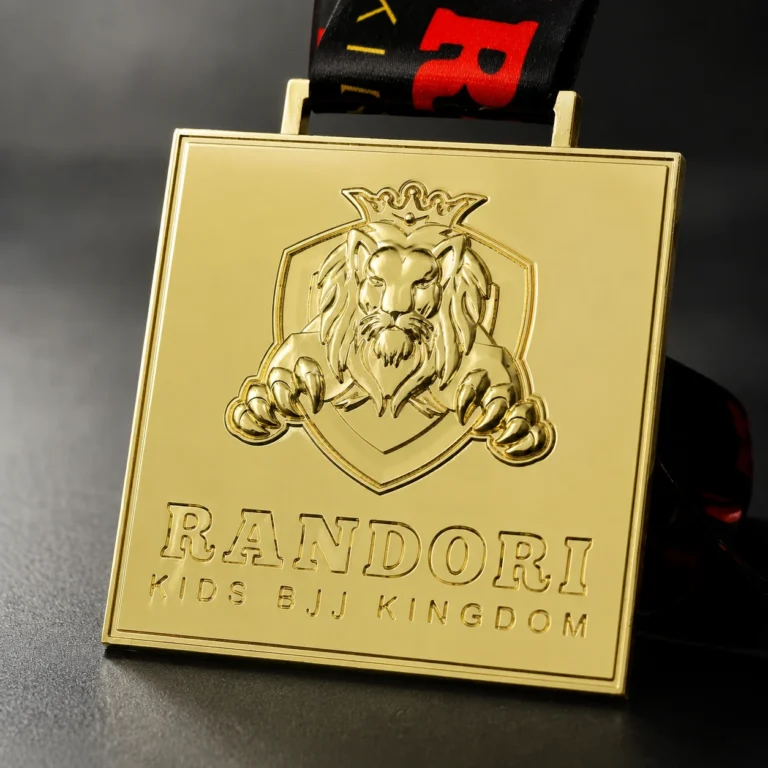 왕관을 쓴 사자 엠블럼과 "RANDORI KIDS BJJ KINGDOM" 문구가 있는 사각형 금메달, 검정색과 빨간색 리본에 부착됨.