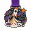 Medaille der Wissenschaftsolympiade "Rocket Trail" aus weicher Emaille mit antikbronzefarbenen Metallkonturen, lila Band, Kontur der Raketenfahne, Planetenring, Laborbrille und weißem Hintergrund.