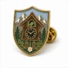 Shield Cuckoo Clock Pin aus weichem Emaille mit erhabenen Metallkonturen, flachen Emaille-Farbabschnitten, verbundenen Abzeichendetails und einem Schmetterlingsgriff auf weißem Hintergrund.