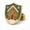 Alfiler de esmalte blando Shield Gingerbread House Pin con contornos metálicos en relieve, secciones planas de esmalte de color, detalles de insignia conectados y un embrague de mariposa sobre fondo blanco.