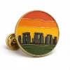 Sunset Stonehenge Pin soft enamel pin with raised metal outlines, flat enamel color sections, connected badge details, and a butterfly clutch on a white background.