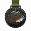 Медаль Tough Mudder Medal из мягкой эмали с контурами из черного никелированного металла, зеленой лентой, контуром в форме шины, грязной тропой, узлом из веревки, брызгами воды, горным хребтом и белым фоном.
