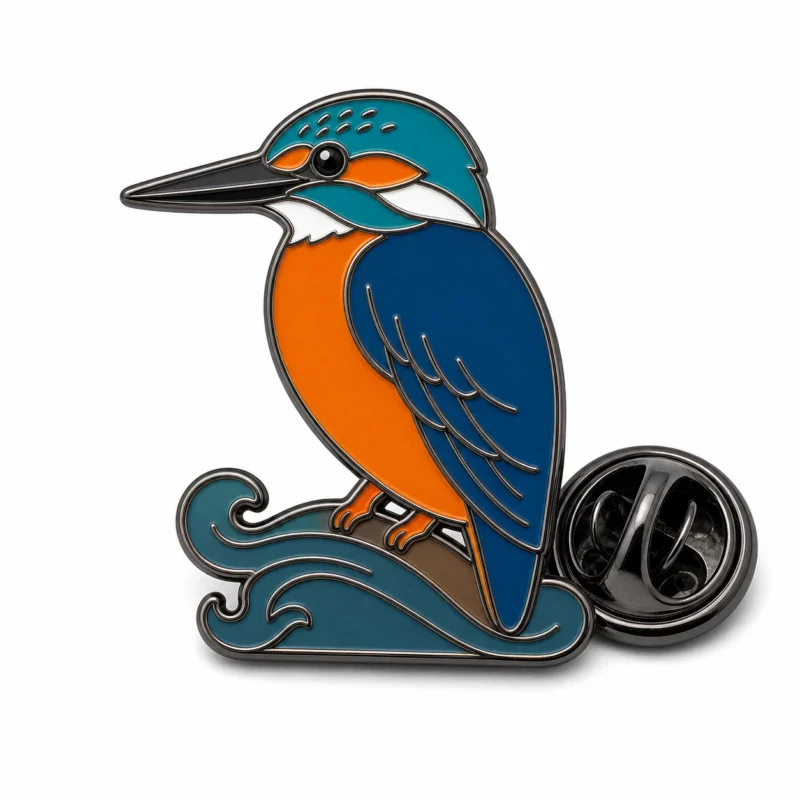 Épingle de martin-pêcheur à branches ondulées avec contours en nickel noir, aile bleu foncé, tête turquoise, ventre orange, base incurvée, et une pochette de papillon sur fond blanc.