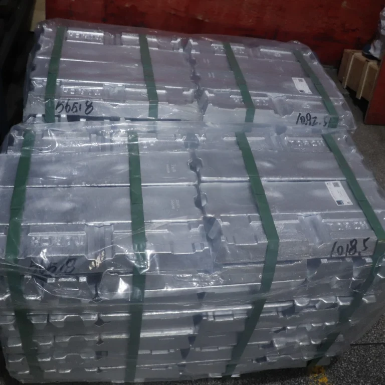 A pallet of new zinc alloy raw materials, neatly stacked and secured with green straps and plastic wrap, ready for storage or transport.