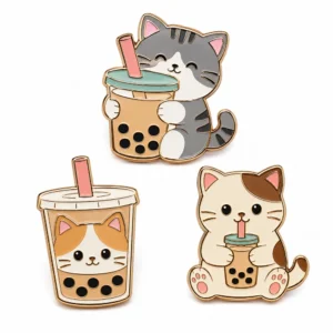 Custom boba cat pins set with grey and calico cats, bubble tea cups, gold metal outlines, black tapioca pearls, and pink straws on a white background.