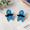 Two custom blue awareness ribbon enamel pins featuring black mustaches, polished silver-tone outlines, and a clean men’s health support design.