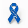 A custom blue awareness ribbon enamel pin with polished silver-tone outlines, raised “Grow a Mo” lettering, and a small mustache symbol.