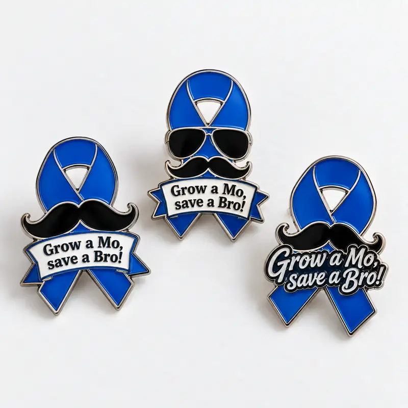 Three custom blue awareness ribbon enamel pins featuring black mustaches, polished silver-tone outlines, and “Let it grow!” lettering in three different designs.